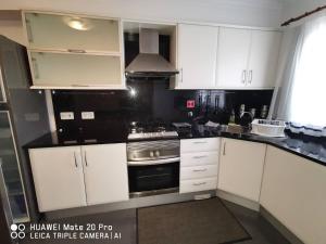 a kitchen with white cabinets and a stove top oven at Andrade Blue in Caniço