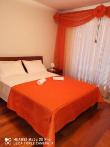 1 Schlafzimmer mit 2 Betten mit orangefarbener Bettwäsche und einem Fenster in der Unterkunft Andrade Blue in Caniço