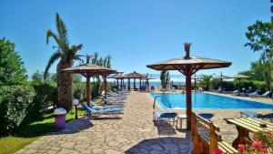 a row of chairs and umbrellas next to a swimming pool at NEFELI House in Lefkimmi