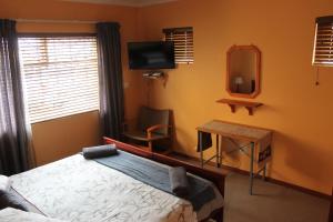 um quarto com uma cama, uma secretária e uma televisão em The Timeless Way Self Catering Accommodation em Swakopmund