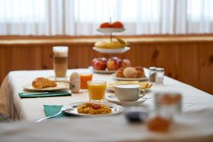 阿罗萨Hotel Sonnenhalde, Arosa的摆放着早餐食品和饮料的桌子