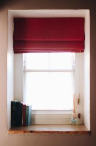 a window with a red curtain and books on a shelf at Llys Meddyg in Newport
