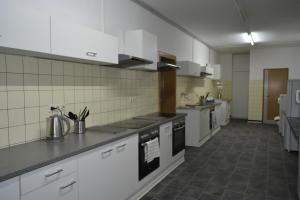 eine große Küche mit weißen Schränken und Geräten in der Unterkunft Pension Highway 3 in Bielefeld