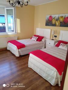 1 dormitorio con 2 camas con sábanas rojas y blancas en Calle Maliayo, en Villaviciosa