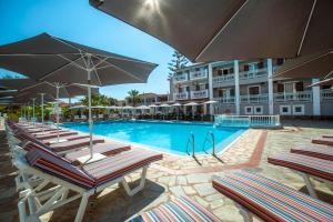 a swimming pool with chairs and umbrellas next to a hotel at Anamar Zante Hotel in Argassi