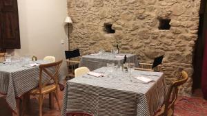 a dining room with two tables with chairs and a stone wall at Hostal de Bianya in Vall de Bianya