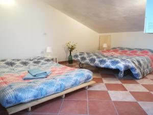 two beds in a room with a tiled floor at Casa Arcobaleno in Siena