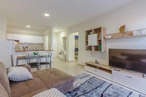 sala de estar con sofá y TV y cocina en Seguro Spacious apartment with roomy terrace, en Puerto de Santiago