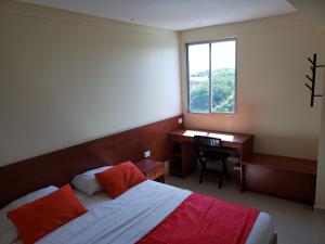 a bedroom with a bed and a desk and a window at Hotel Sandiego inc in Barranquilla
