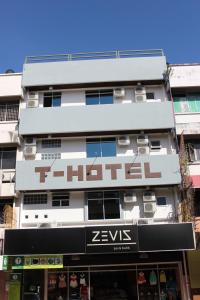 een hoog wit gebouw met een bord erop bij T Hotel in Tawau