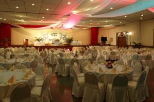 um grande salão de banquetes com mesas e cadeiras brancas em Almont Inland Resort em Butuan