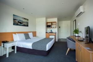 Schlafzimmer mit einem Bett, einem Schreibtisch und einem TV in der Unterkunft Harbourside Lodge in Nelson