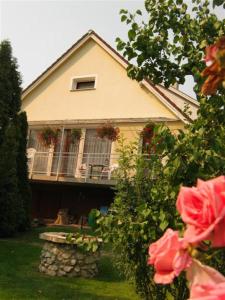 una casa con balcón y rosas frente a ella en Naszály Kapuja vendégház, en Kosd