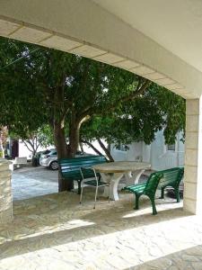 een picknicktafel en twee groene banken onder een boom bij Apartments Nazario in Drvenik