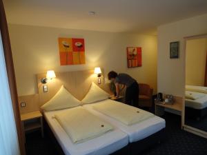 a woman in a hotel room with a bed at Landgasthof Hock in Großostheim