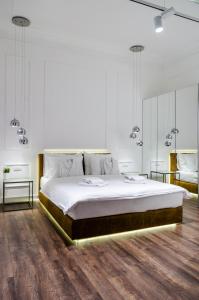 ein weißes Schlafzimmer mit einem großen Bett und 2 Tischen in der Unterkunft Room 25 Belgrade in Belgrad