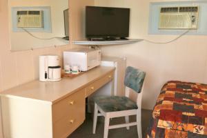 a room with a desk with a microwave and a bed at Sunset Motel in Creston