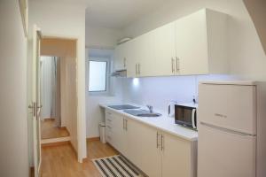 eine weiße Küche mit einer Spüle und einem Kühlschrank in der Unterkunft Casa do Colégio Downtown Private Suite 57 in Ponta Delgada