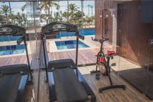 a gym with a treadmill and a swimming pool at Pajuçara Praia Hotel in Maceió