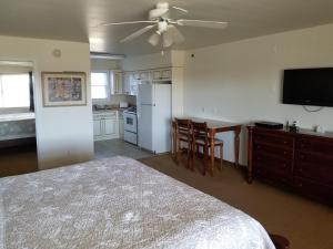 a bedroom with a bed and a kitchen with a ceiling fan at Shore Stay Suites in Cape Charles