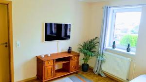 Zimmer mit einem TV an der Wand und einer Holzkommode in der Unterkunft Ferienwohnung Dahlenwarsleben in Dahlenwarsleben