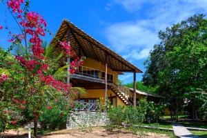 a house with a thatched roof and flowers at LAGO HOTEL PIPA - TlBAU DO SUL in Pipa