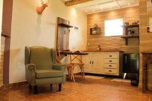 a living room with a green chair and a desk at Fazenda Morro Pelado in Águas de Lindóia