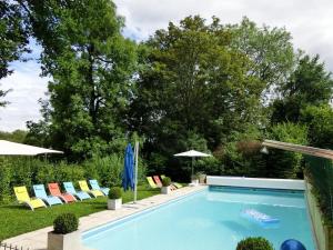 a swimming pool with lawn chairs and umbrellas at Chateau Saint Claude an der Saone in Mantoche