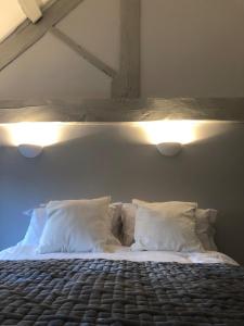 a bedroom with a bed with two pillows and lights at Fossewold Cotswold Barn in Chipping Campden