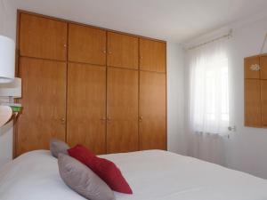 1 dormitorio con 1 cama con armarios de madera y almohadas rojas en Casa Eugenia, en Sesimbra