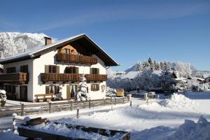 Casa cubierta de nieve con balcón en la nieve en Ferienwohnungen Wurzer Toni, en Grainau