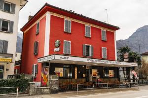 a red building on the side of a street at Hotel della Posta in Biasca