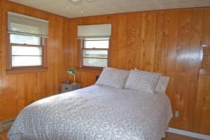 Caster Holdings Too! في ميستيك: غرفة نوم بسرير وجدران خشبية ونوافذ
