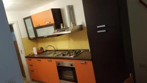 een keuken met oranje kasten en een zwarte koelkast bij Casa vacanze Arimondi in Porto Cesareo