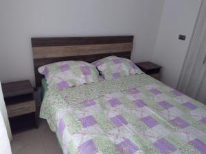 a bed with a purple and green quilt and two pillows at Departamento temporada in Coquimbo