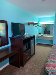 ein Hotelzimmer mit einem TV, einem Bett und einem Schreibtisch in der Unterkunft Scottish Inn - Clanton in Clanton