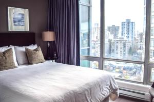 a bedroom with a white bed and a large window at Vancouver Extended Stay in Vancouver