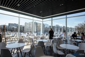 a room with tables and white chairs and windows at Apart Assistant on Smart Plaza in Kyiv