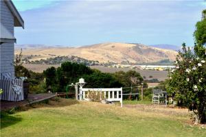 a house with a white fence and mountains in the background at Watson Park in Yankalilla