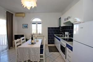 una cucina con un tavolo e un frigorifero bianco di Apartments Mara a Supetar (San Pietro di Brazza)