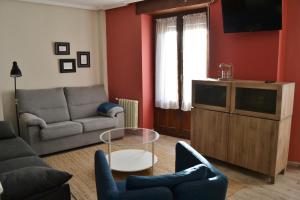 Una sala de estar con un sofá y un televisor. en Tres Puentes Anguiano Apartamentos y Hostal, en Anguiano