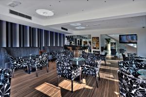 ein Restaurant mit schwarzen und weißen Stühlen und Tischen in der Unterkunft Livadhiotis City Hotel in Larnaka