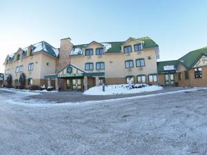 a large building with snow in front of it at Travelodge by Wyndham Lacombe in Lacombe