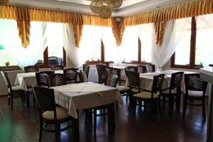 a dining room with tables and chairs and windows at Elegance Spa Hotel in Ognyanovo