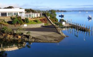 a large body of water with a dock and a building at The Camel at Araiawa Raio Lodge Pukenui in Pukenui