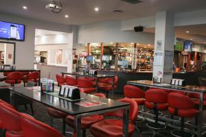 a restaurant with red chairs and tables and a bar at Acacia Ridge Hotel & Motel Brisbane in Brisbane