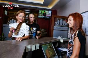 dos mujeres y un hombre de pie en un mostrador en Elegance Spa Hotel en Ognyanovo
