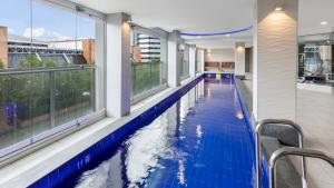 a swimming pool in a house with a large window at Oaks Adelaide Embassy Suites in Adelaide