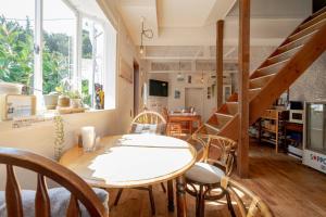 a dining room with a table and chairs and a staircase at Beach Side Inn Shirahama in Shimoda