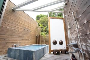 a bathroom with a soaking tub in a wooden wall at Beach Side Inn Shirahama in Shimoda